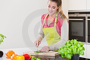 Woman in kitchen cutting herbs