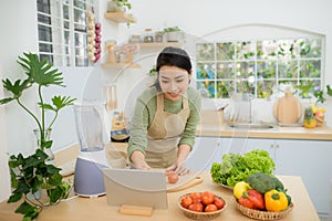 Woman In Kitchen Following Recipe On Digital Tablet