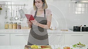 Woman in kitchen following recipe on digital tablet computer