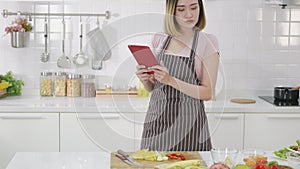 Woman in kitchen following recipe on digital tablet computer