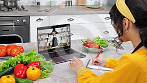 Woman in kitchen greets study online video call laptop listen chef writes