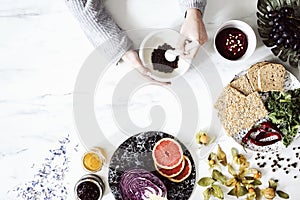 Woman in the kitchen and her healthy food eating selection: fruits, vegetables, super food, seeds, marble background copy space. photo