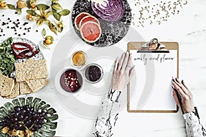 Woman in the kitchen and her healthy food eating selection: fruits, vegetables, super food, seeds, marble background copy space. photo