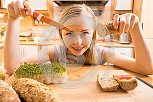 Woman in kitchen holding knife making healthy sandwich