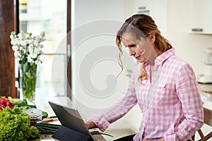 Woman in the kitchen looking for recipes on the tablet