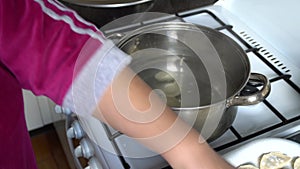 Woman in the kitchen near a gas cooker in a saucepan dumplings for cooking