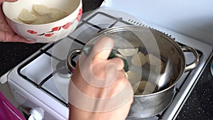 Woman in the kitchen near a gas cooker in a saucepan dumplings for cooking
