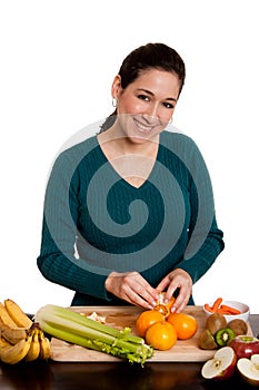 Woman in kitchen peeling orange