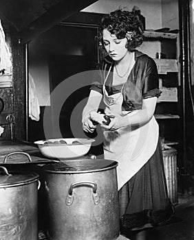 Woman in a kitchen peeling potatoes