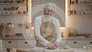 Woman In Kitchen Prepares. She Is Preparing For New Year Holidays. She Cute Grandmother With Gray Hair. Grandmother