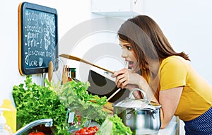 Woman in kitchen reed menu and cooking