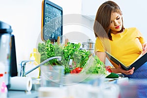 Woman in kitchen reed menu and cooking