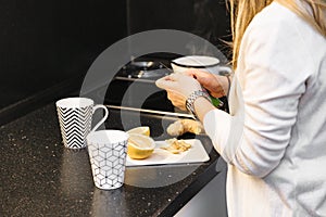 Woman in kitchen slicing lemon to make some tea