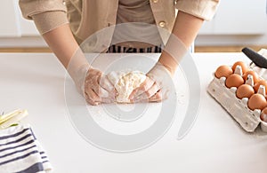 Woman kneading dough for Italian Grissini at white table in kitchen, close-up.