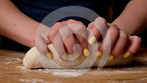 Woman kneads dough with her hands on table at home.