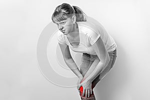 Woman with knee pain is holding her aching leg