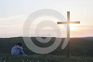 Repentance. A woman is kneeling. Near the cross. Prayer of repentance. Christian faith. photo