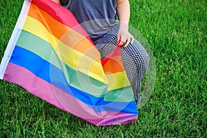 A woman knelt with a LGBT flag, background green grass in the Park. Concept of anti-racism protests and demonstrations in USA