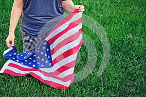 A woman knelt with a US flag, background green grass in the park