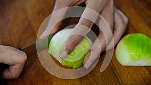 Woman with knife cutting onion.