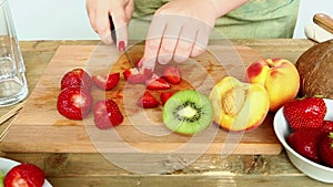 Woman knife regimen of strawberries for fruit salad