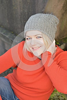 Woman with knit hat sitting and leaning against a stone