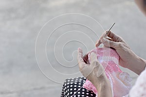 The woman knits a hook from a pink and white yarn.