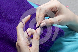 A woman knits knitting, lying in bed. A product made of string of purple.