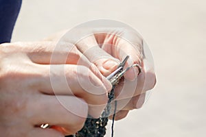 Woman knits on knitting needles out of wool on the street on a sunny day.