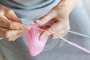 A woman knits a pink canvas with spokes. Hands close-up.