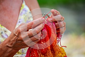 A woman knits a scarf with natural yarn