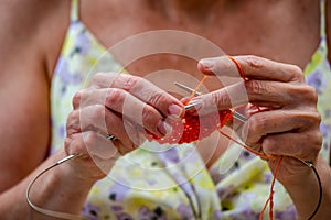 A woman knits a scarf with natural yarn