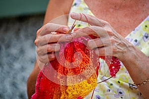 A woman knits a scarf with natural yarn