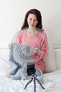 A woman knits sitting on a bed