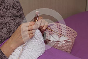 The woman knits. Sitting in my pajamas under the covers. Close-up shot.