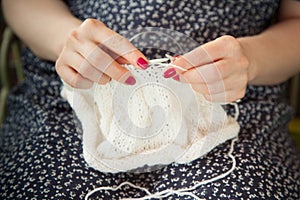 A woman knits a white canvas with spokes. Hands close-up.