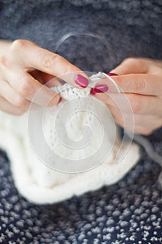 A woman knits a white canvas with spokes. Hands close-up.