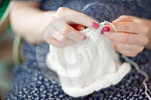 A woman knits a white canvas with spokes. Hands close-up.