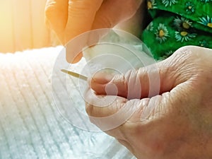 A woman knits a white scarf with knitting needles and threads