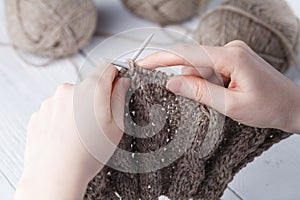 The woman knits woolen clothes. Knitting needles. Close-up. natural wool