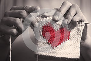 Woman knitting the red heart for her loved one.