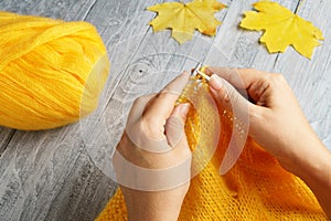 The woman knitting a thing with yellow yarn