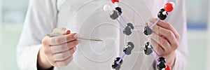 Woman in lab coat demonstrates molecule model in hands