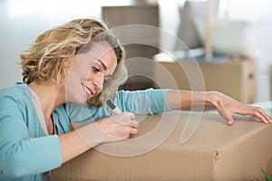 woman labelling cardboard box for moving house