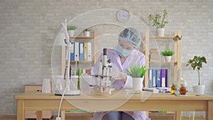 Woman laboratory assistant conducts a study of the plant with a microscope in a modern laboratory