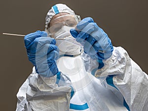 A woman, laboratory technician, completely covered in a white protective suit, makes a test swab to check for Covid-19 Coronavirus