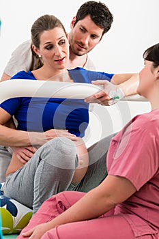 Woman laboring in delivery room with nurse and husband