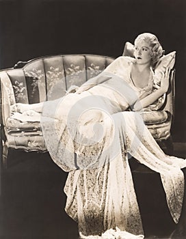 Woman in lace gown lounging on sofa