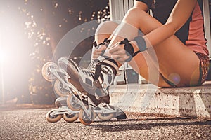 Woman laces up her skates sitting on curb