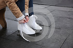 Woman lacing figure skate outdoors, closeup. Space for text